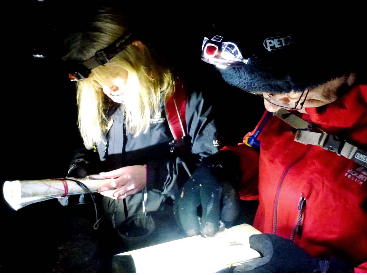 Head torches light up a map and compass during a night navigation low visibility course on New Forest heathland